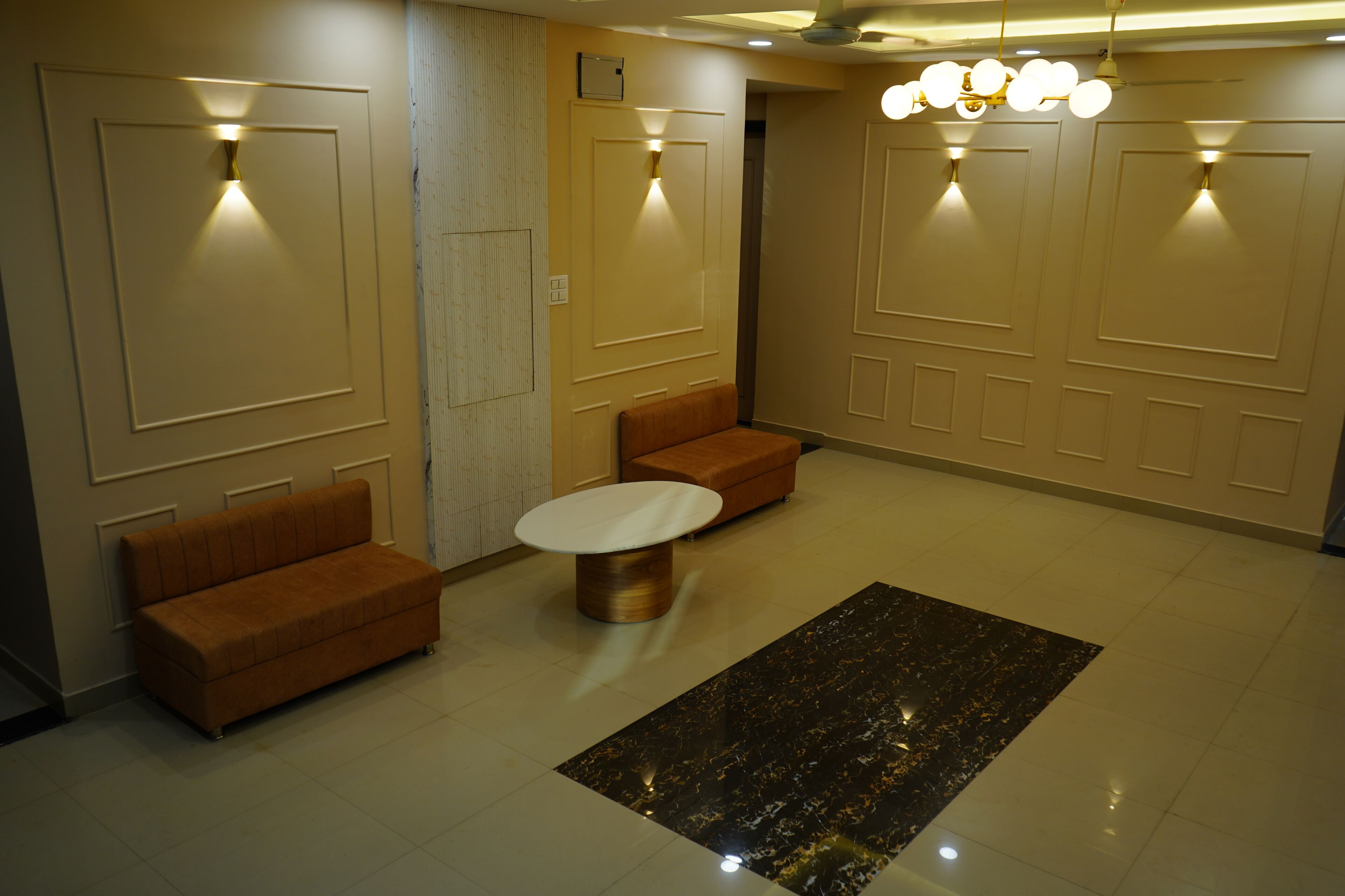 A hotel lobby with a reception desk, two sofas, a coffee table, and a chandelier.