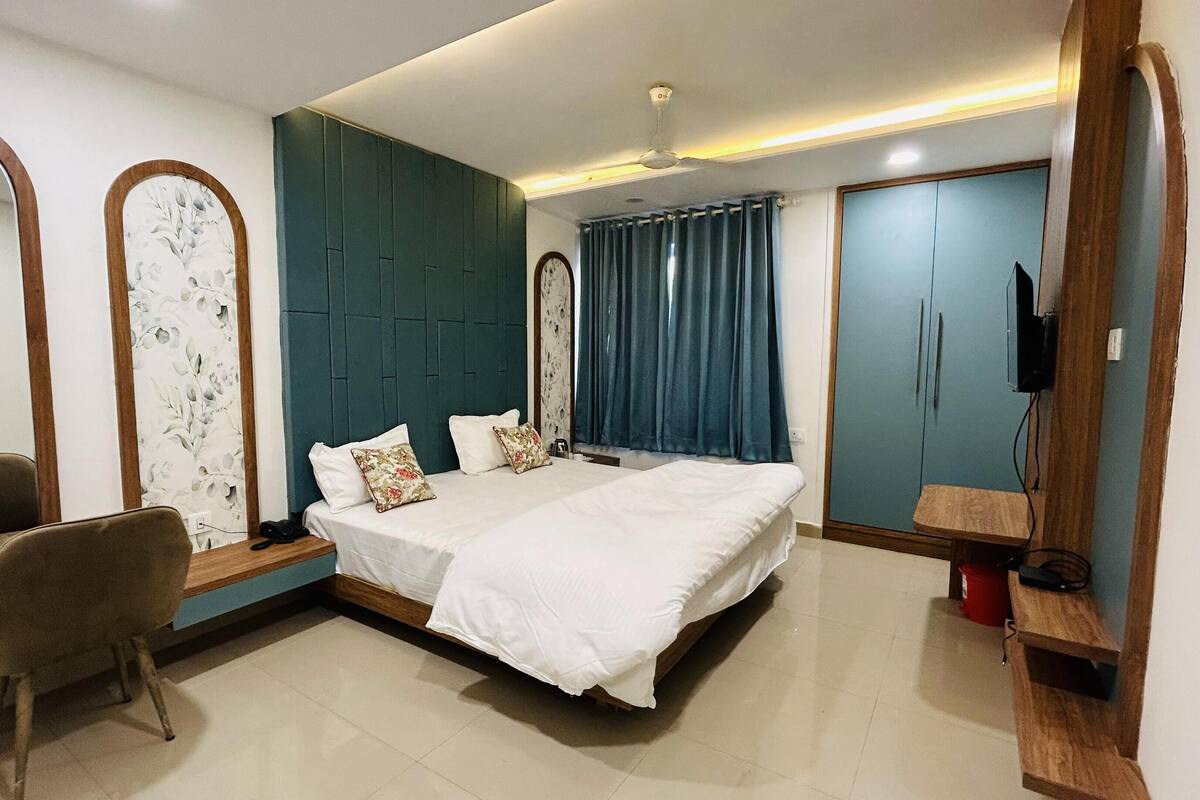 A modern bedroom with a large bed, a desk, and a wardrobe.
