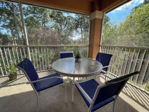 A covered outdoor area with a round table and four chairs, surrounded by a metal railing.
