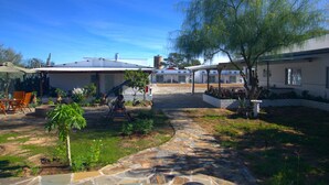 A residential area with a patio, outdoor seating, and a stone pathway. - Little Bush Guesthouse (Omaruru)