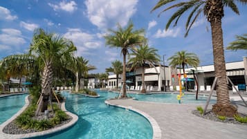 A swimming pool with palm trees and lounge chairs, surrounded by buildings.