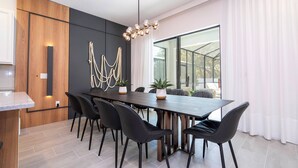 A modern dining area with a long table, black chairs, and a unique chandelier.