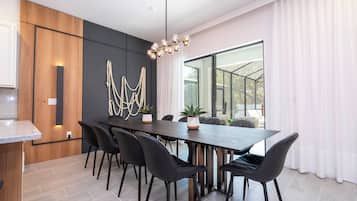 A modern dining area with a long table, black chairs, and a unique chandelier.