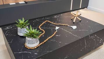 A black marble countertop with two potted succulents, a beaded necklace, and a starfish.