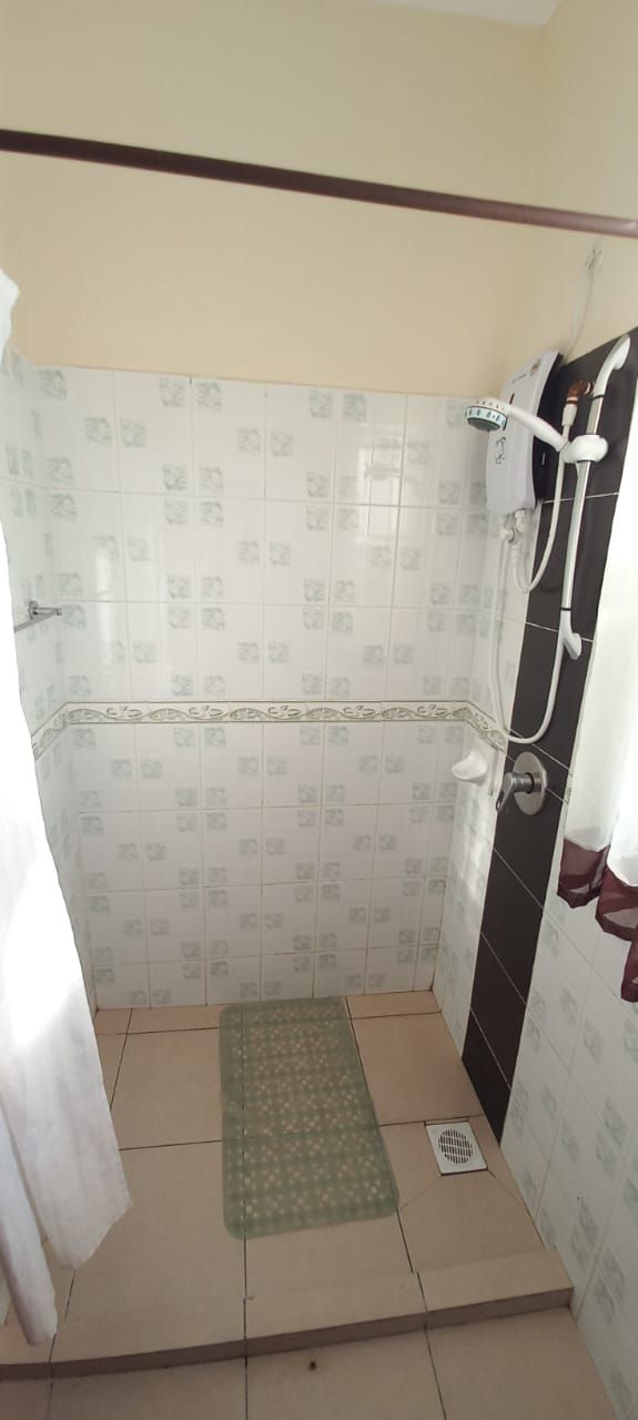 Un espace douche avec un mur carrelé, une pomme de douche et un drain.