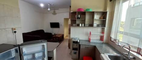 A compact kitchen with a refrigerator, sink, and a small dining area.