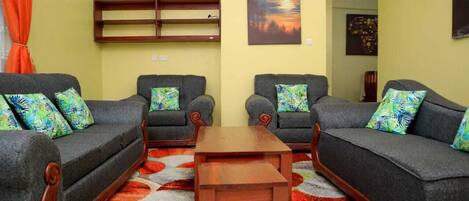 A living room with two sofas, a coffee table, and a wall-mounted shelf.