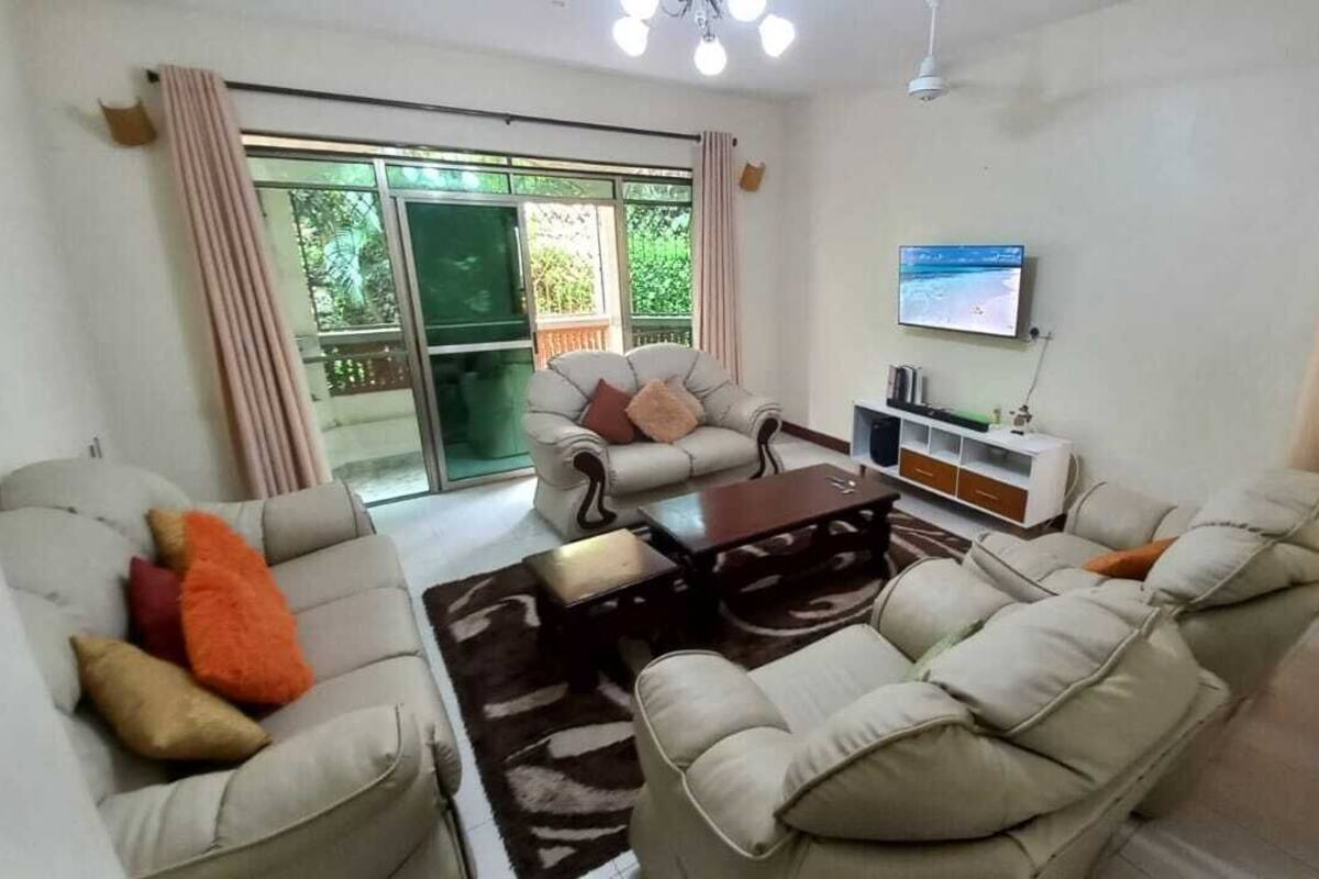 A living room with a sofa set, a coffee table, and a TV mounted on the wall.