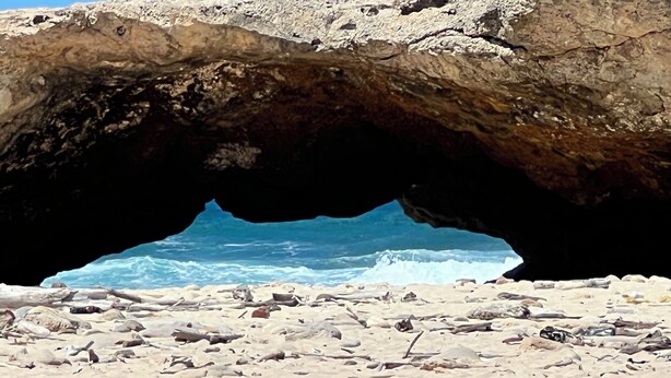 A beach with a large rock formation creating a natural archway.