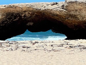 Ein Strand mit einer großen Felsformation, die eine natürliche Bogenform bildet.