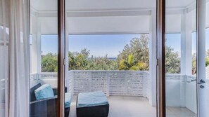 A balcony with a view of greenery and a clear sky.