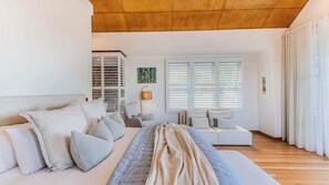 A modern bedroom with a bed, a sofa, and a window with blinds.