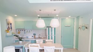 A kitchen with teal cabinets, a white refrigerator, and a dining area with a table and chairs.