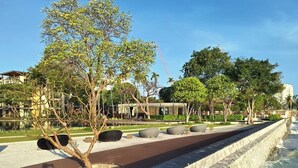 A waterfront promenade with a stone wall, trees, and modern buildings in the background.