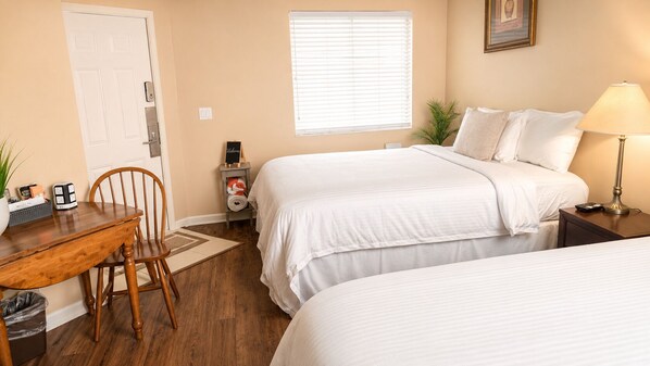 A hotel room with two beds, a desk, a chair, a lamp, a window with blinds, and a welcome sign. - Right Direction Rentals Studio Villa 9113 (Port St. Lucie)