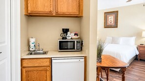 A compact kitchenette with a microwave, coffee maker, and sink.