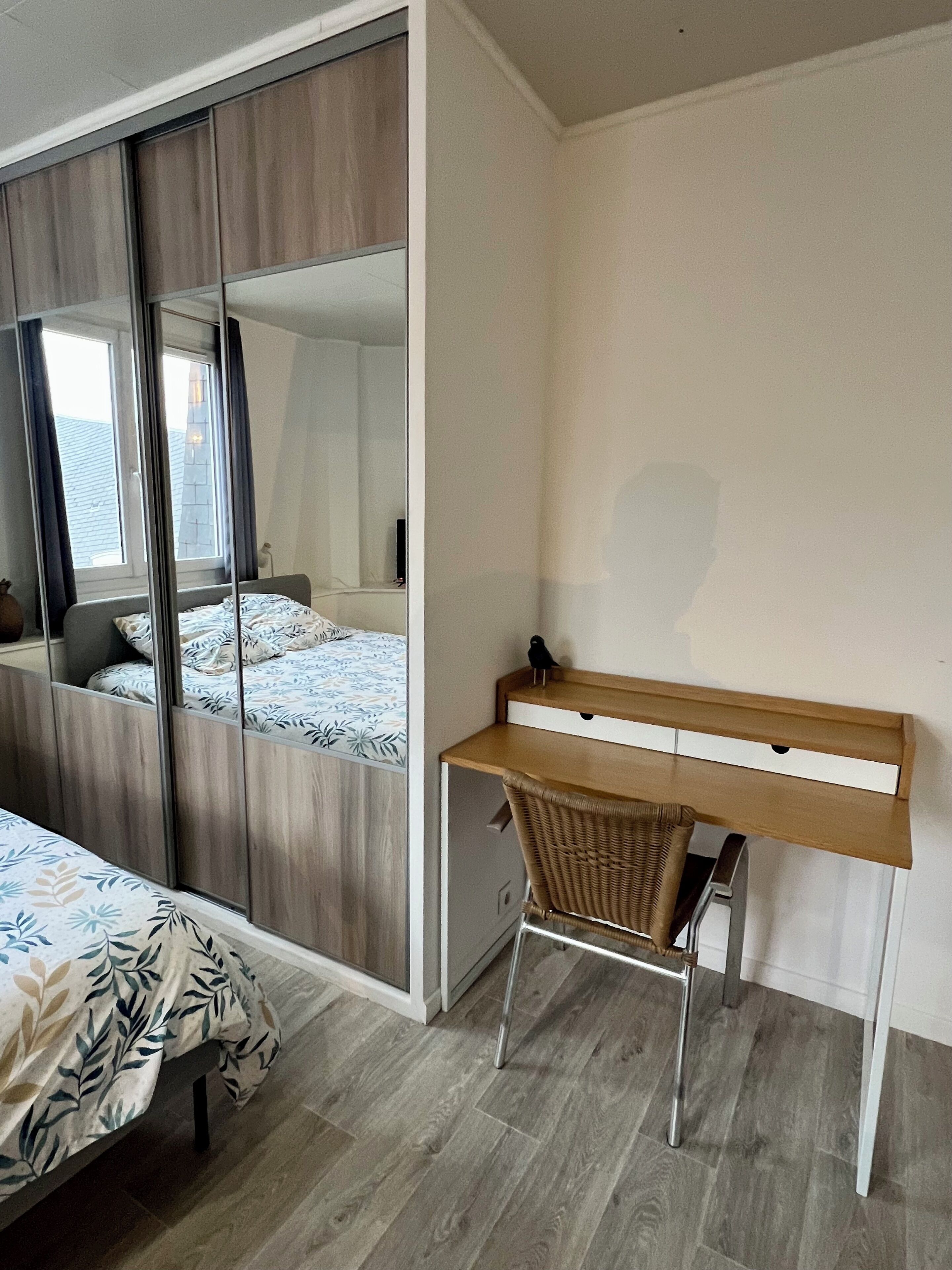 Un dormitorio con cama, escritorio, silla y un espejo grande.