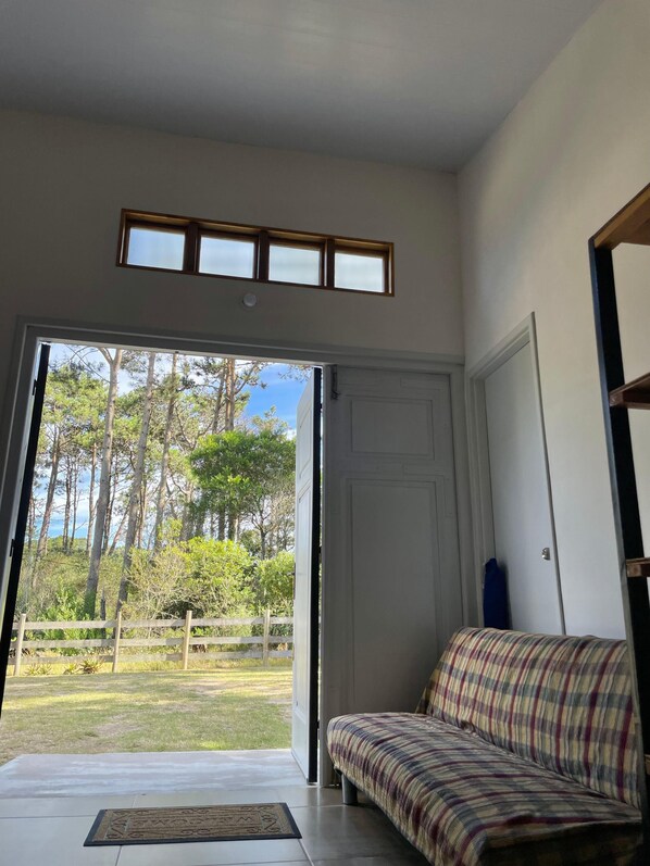 A room with a large sliding glass door leading to a grassy outdoor area, a sofa, and a small table with a mat.