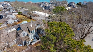A coastal residential area with houses, a clear view of the ocean, and a prominent pine tree. - Maushop Village, 2-bedroom, 1.5 baths, Sleeps 4, A/C, patios & private beach (Mashpee)
