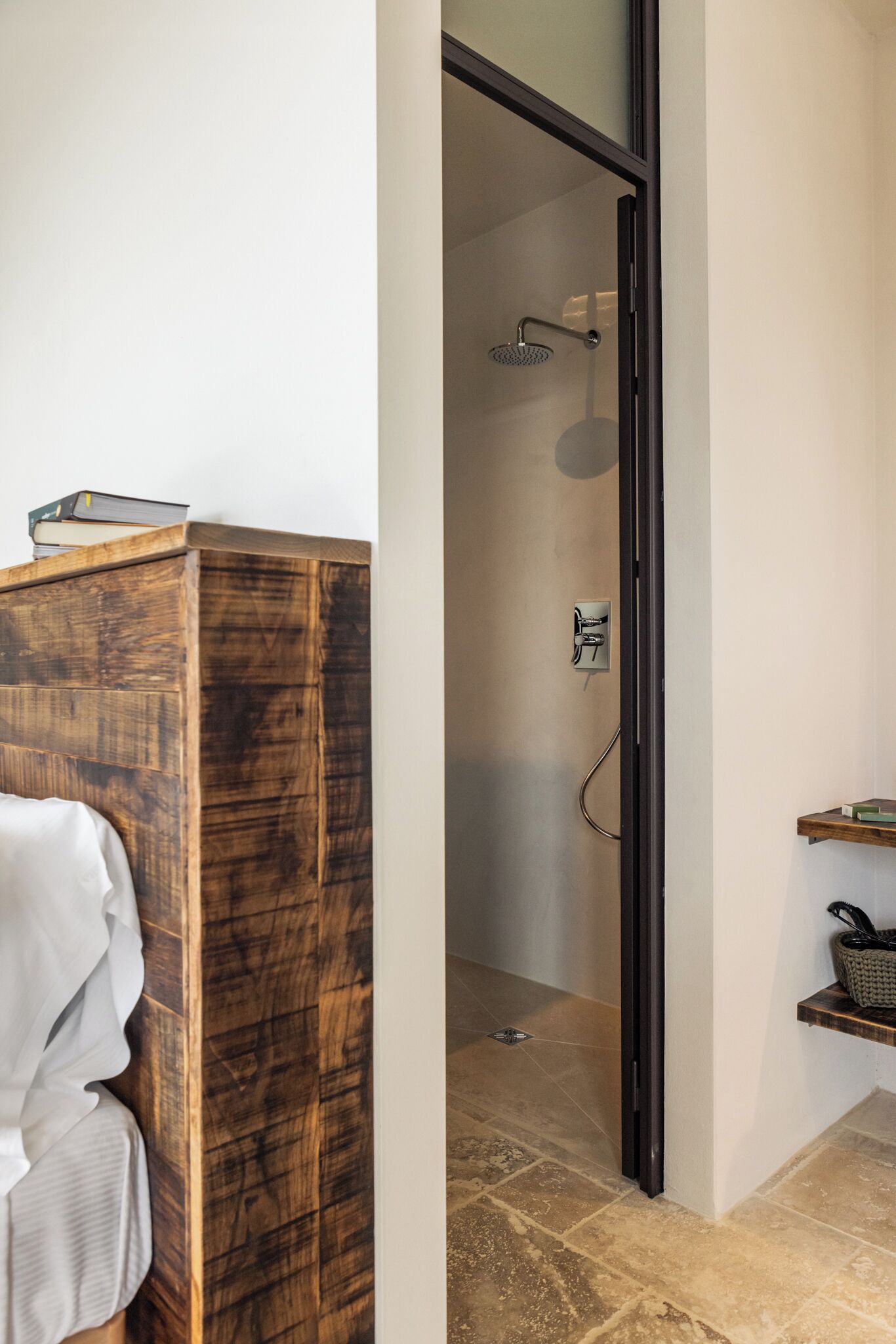 A bathroom with a wooden vanity, a shower with a glass door, and a small shelf with a basket.