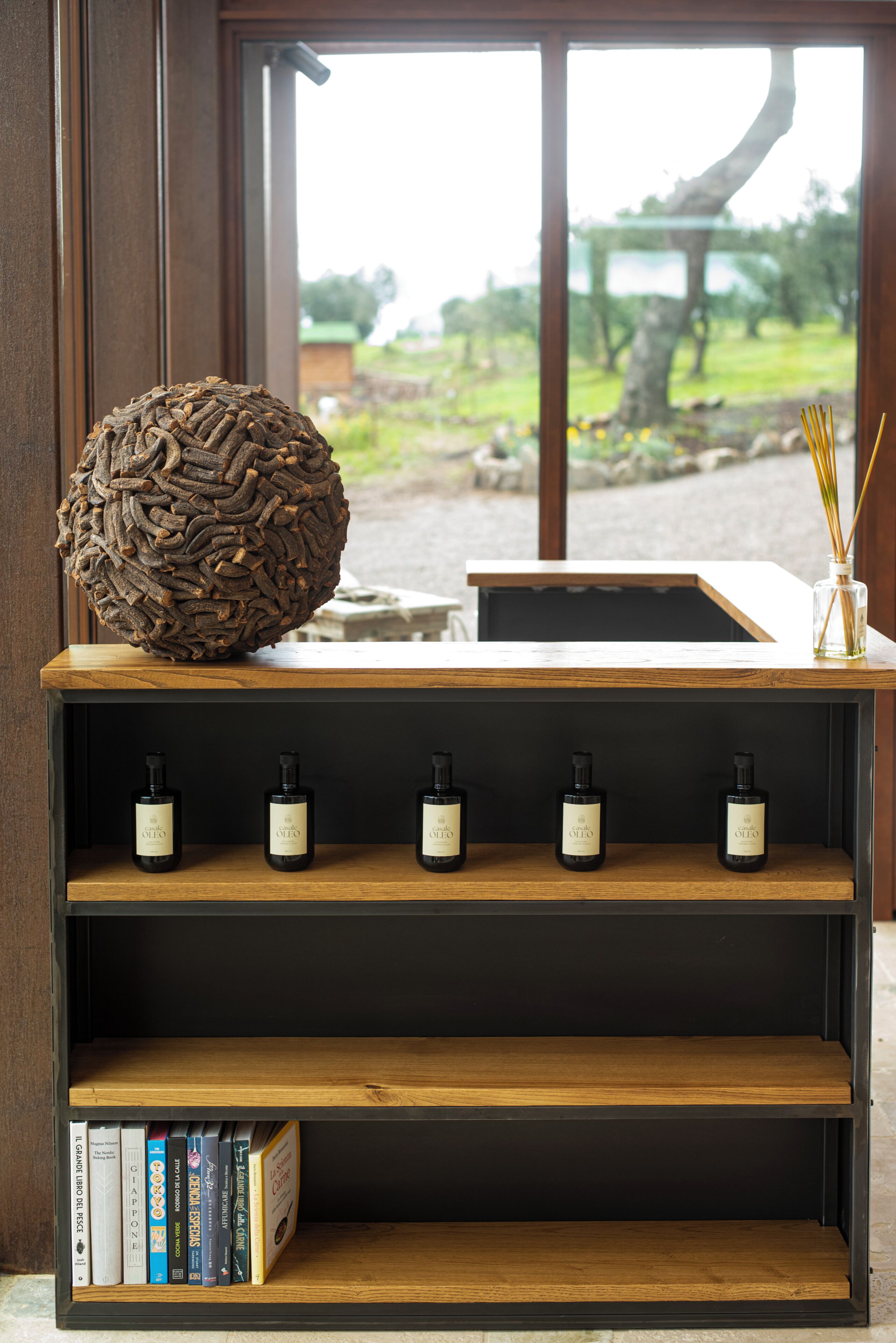 A wooden shelf with books, a decorative sphere, and bottles.