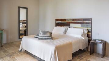 Un dormitorio con una cama grande, cabecera de madera, mesita de noche y espejo.