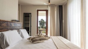 A bedroom with a bed, pillows, a wooden headboard, a wardrobe, and a view through an open door.