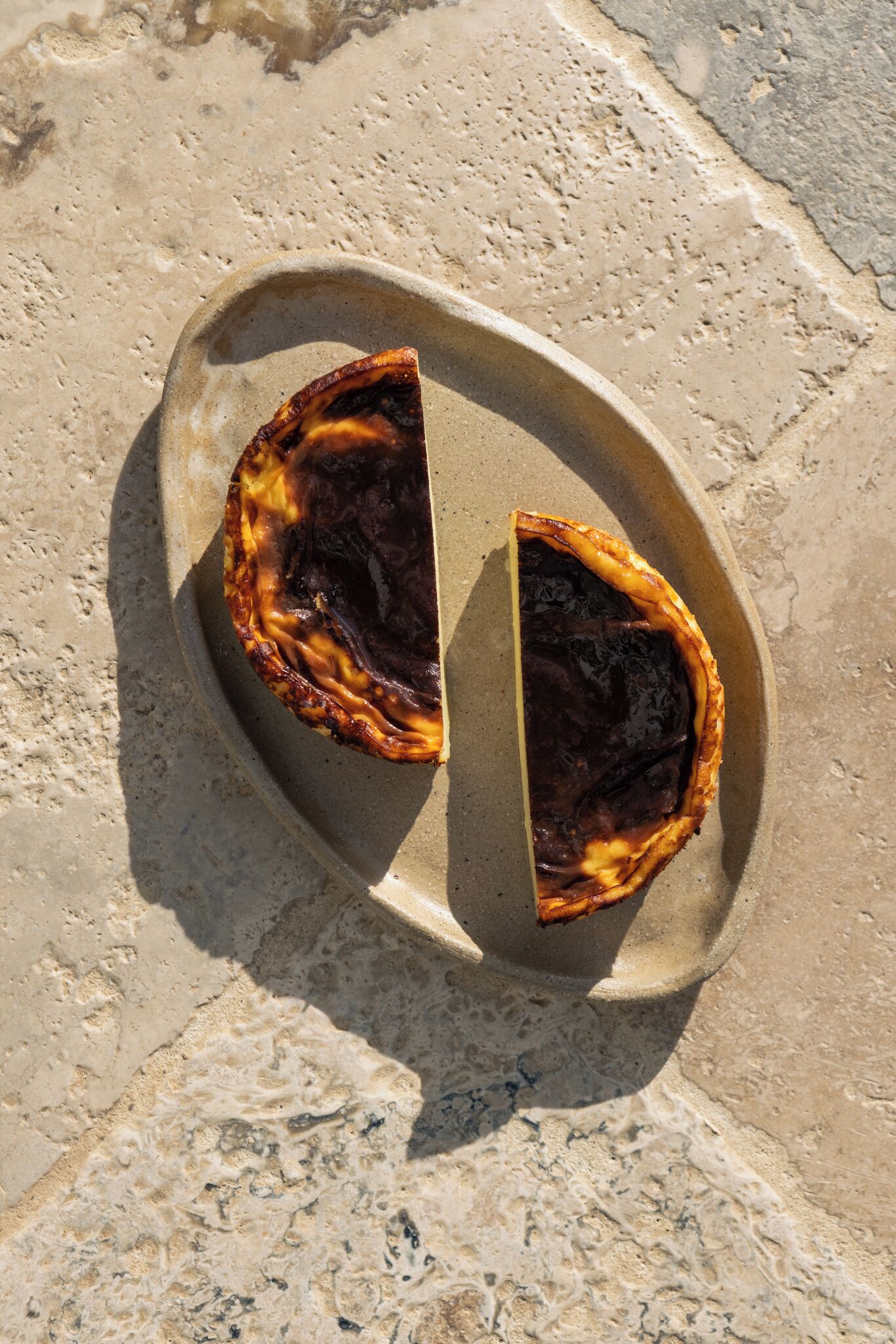 A half-eaten pie on a stone plate on a sandy surface.