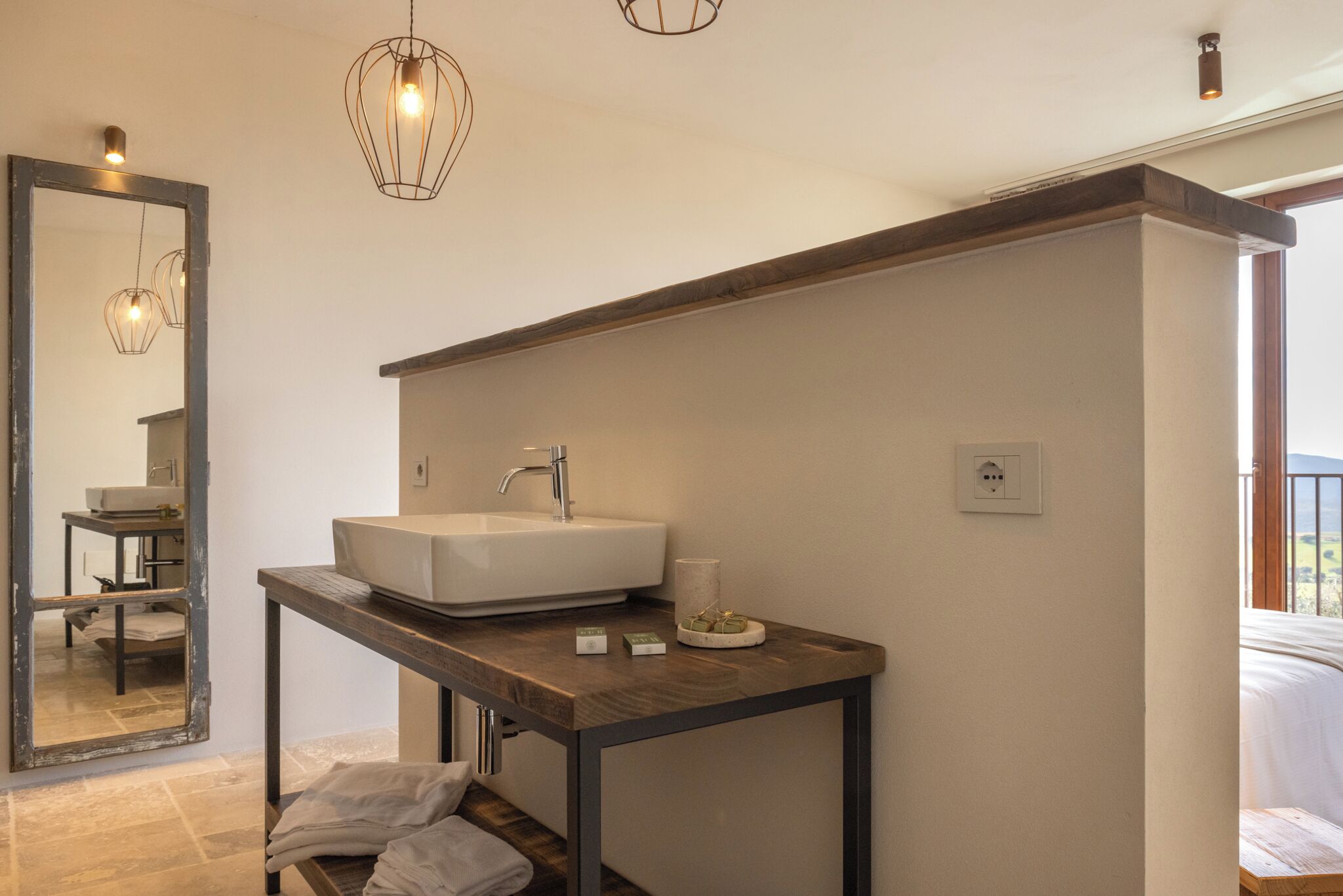 A modern bathroom with a large mirror, a white sink, and a wooden vanity.