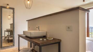 A modern bathroom with a large mirror, a white sink, and a wooden vanity.