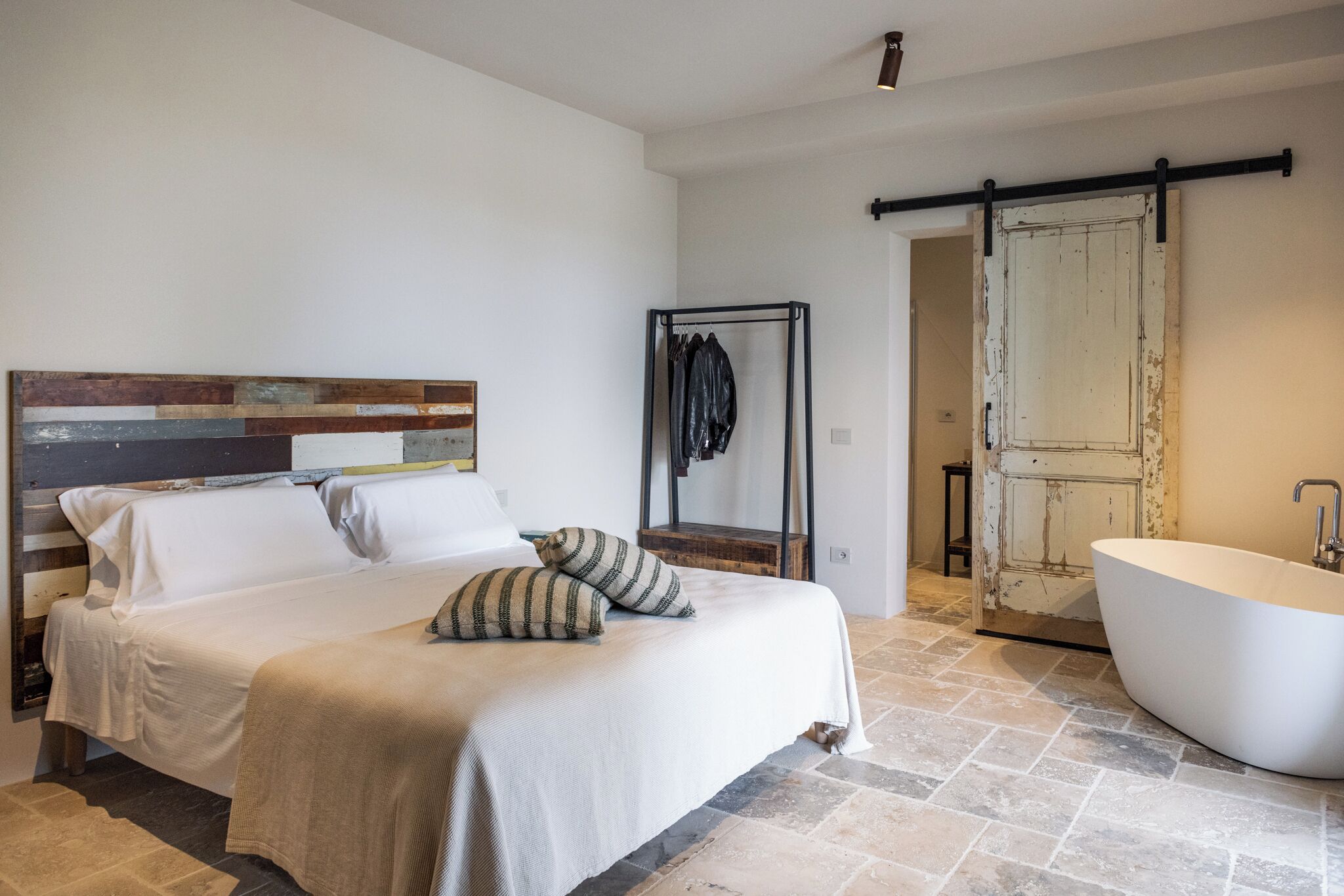 Una camera da letto con un letto, un'ampia finestra e un bagno dotato di vasca e doccia.