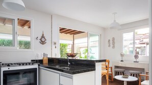 Cocina moderna con estufa, pileta y amplio espacio en las encimeras. Hay dos ventanas que ofrecen luz natural y vistas al exterior.