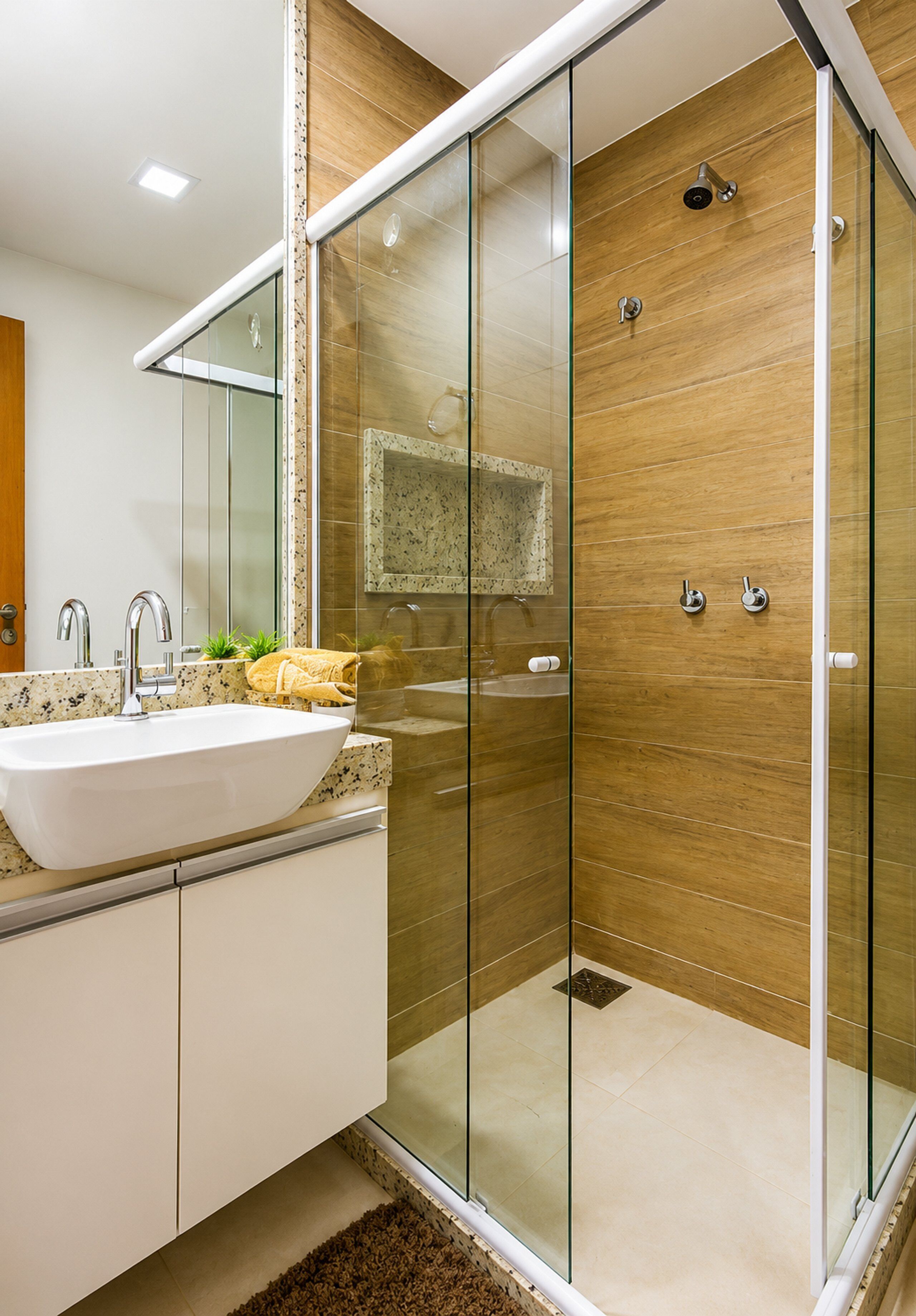 Een moderne badkamer met een glazen douchecabine, een wit wastafelmeubel en een spiegel erboven.