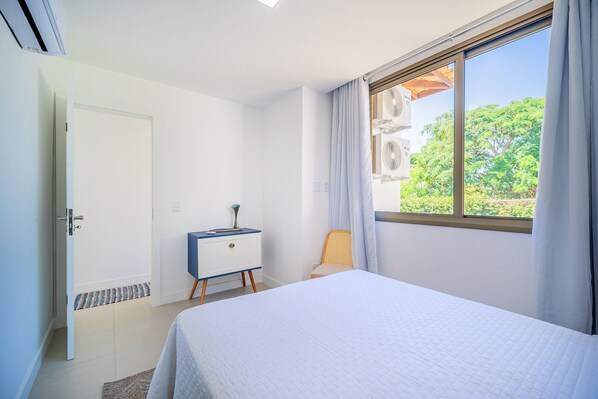 Un dormitorio con cama, cómoda, silla y ventana con cortinas.