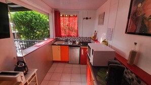 Une cuisine de taille réduite, équipée d’un évier, d’un four à micro-ondes et de placards rouges.