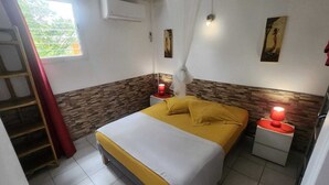 Une chambre à coucher comprenant un lit, deux tables de chevet avec des lampes, une échelle, une fenêtre et un climatiseur fixé au mur.