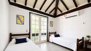 A room with two beds, a door leading outside, and an air conditioning unit on the wall. - House with private pool 300m from the beach! BZ39 (Armação dos Búzios)