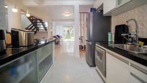 Una cocina moderna con electrodomésticos de acero inoxidable, una encimera negra y vistas a un comedor.