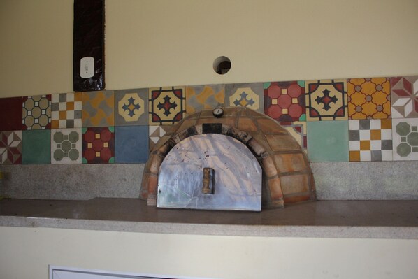 A kitchen with a built-in pizza oven and a colorful tile backsplash.