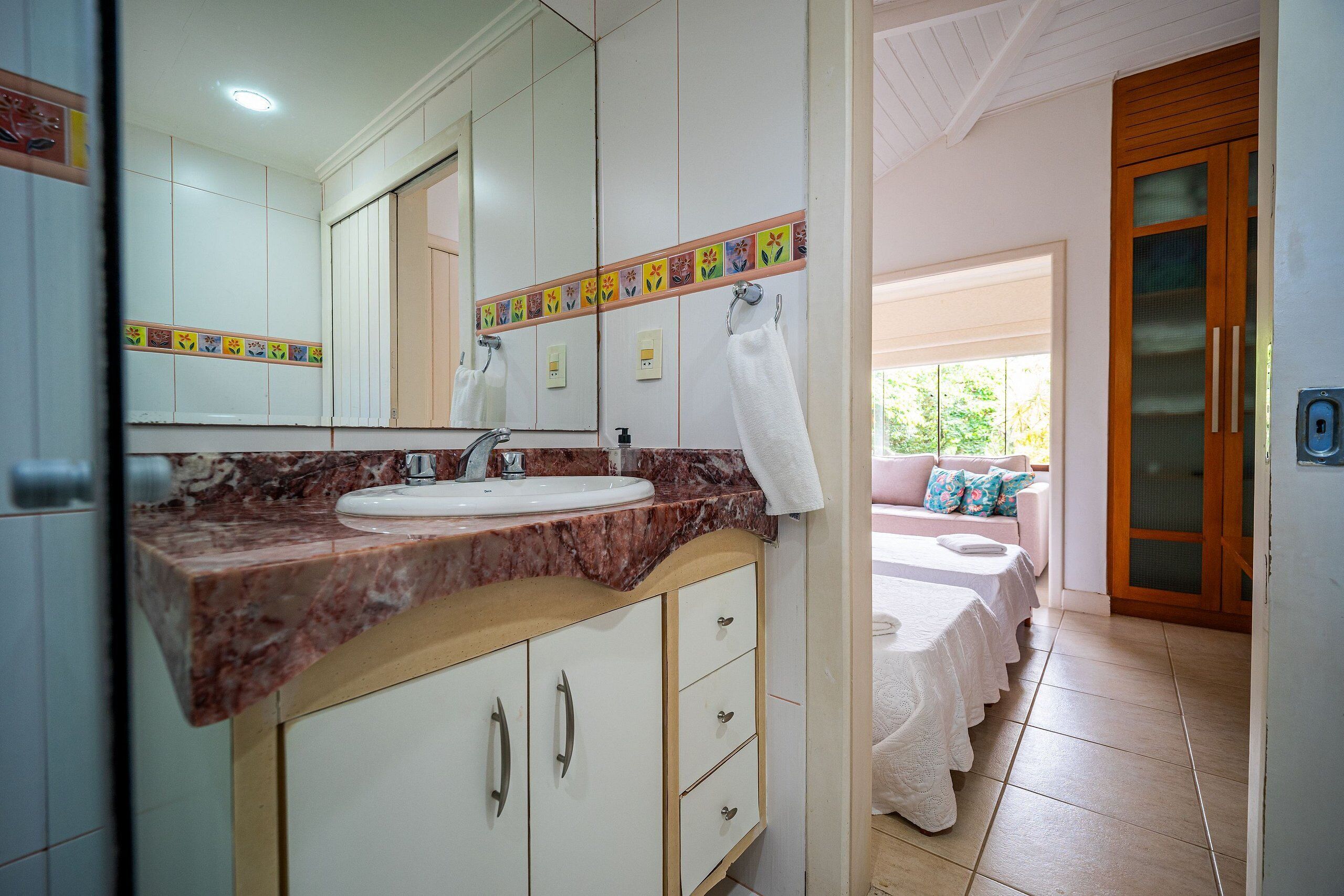 Ein Badezimmer mit Marmorplatte, Waschbecken, Spiegel und einem an der Wand hängenden Handtuch.