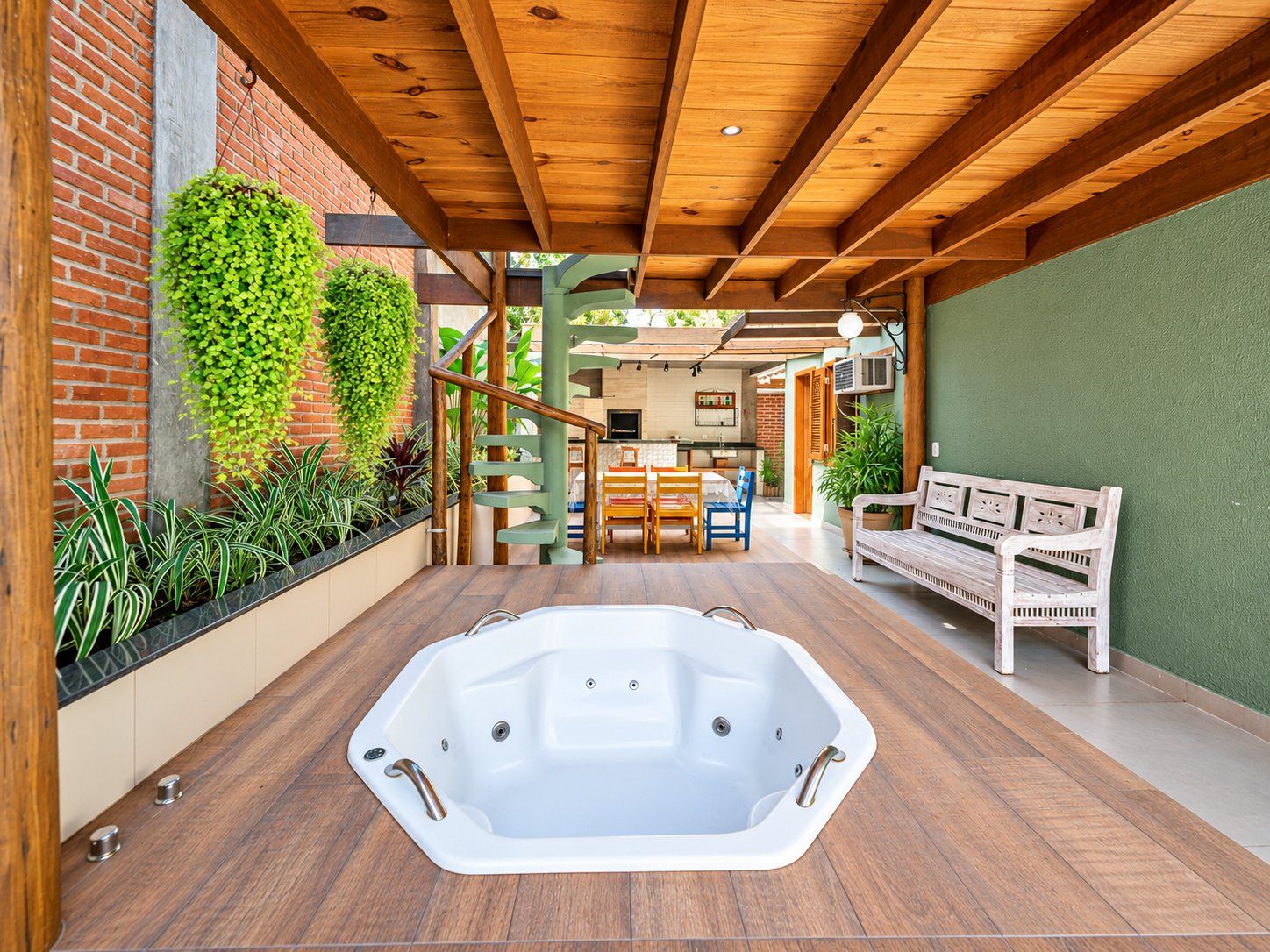 A spa area with a hot tub, wooden flooring, a bench, and a staircase leading to an upper level.