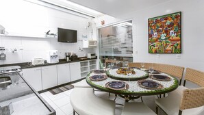 Une cuisine moderne avec des meubles blancs, un four à micro-ondes et un coin repas agrémenté d’une table ronde pour quatre personnes.