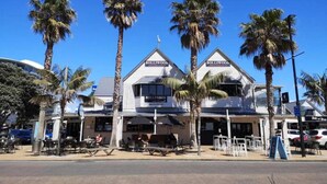 A two-story building with a sign reading "Bollwood." - Modern Orewa Delight w Parking just Steps to Beach (Auckland Hibiscus Coast)