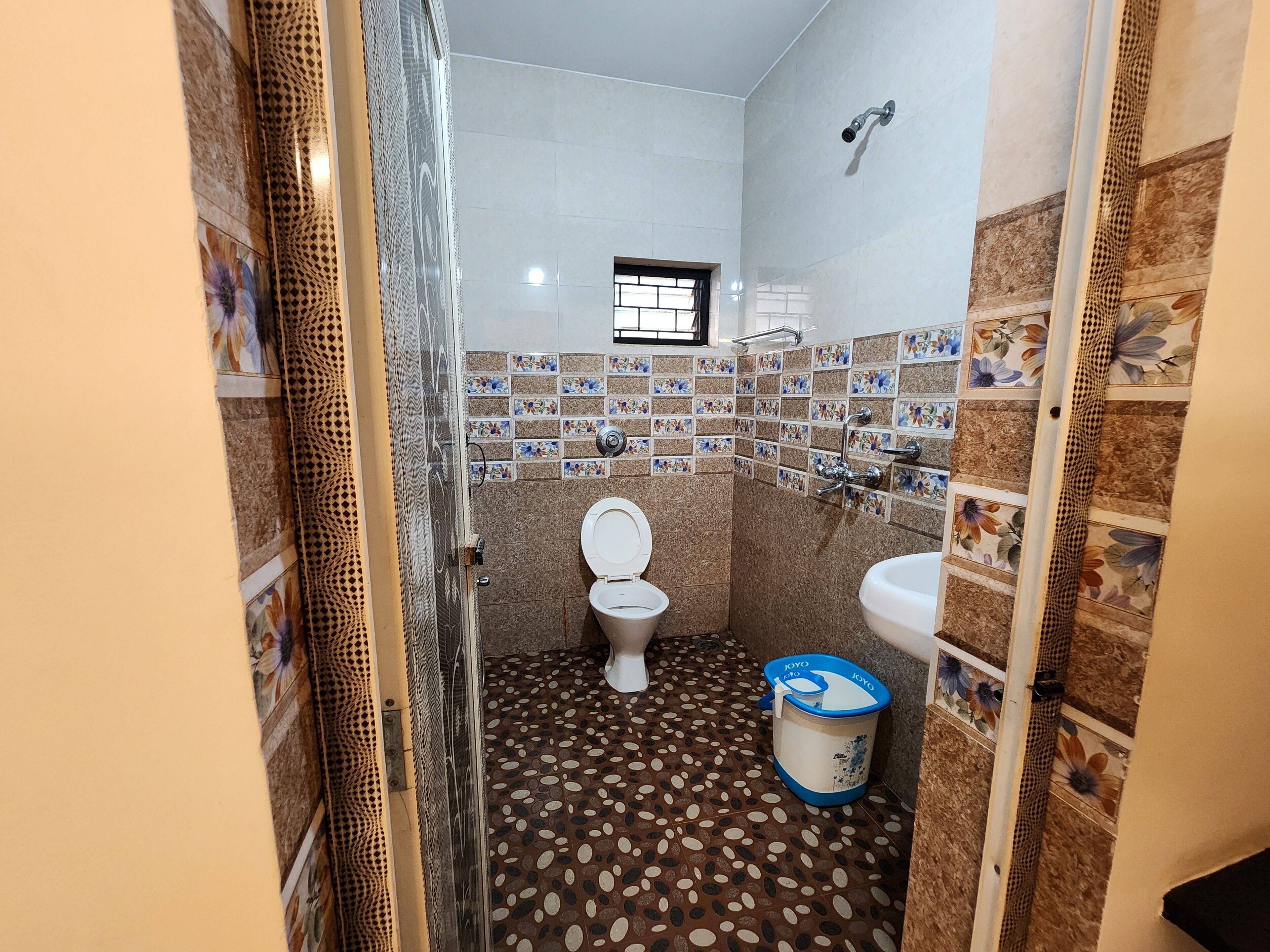 A bathroom with a toilet, sink, shower, and patterned floor tiles.