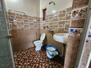 A bathroom with a toilet, sink, and shower. The walls are tiled with floral patterns, and the floor has a polka dot design. - Sai Sharad Hotel  (Pernem)