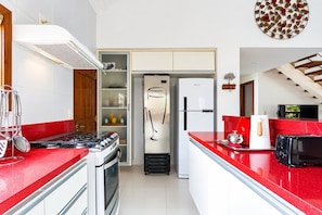 A kitchen with a gas stove, a refrigerator, and a microwave.