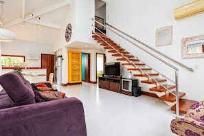 A spacious living area with a modern staircase, a dining area, and a kitchen.