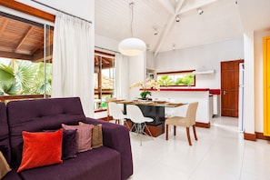 A modern living room with a purple sofa, dining area, and kitchen.