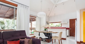 A modern living space with a dining area, kitchen, and large windows.