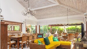 A spacious indoor area with a large wicker sofa, dining table, and chairs. - Bz37 House with Pool 200M from the beach! (Armação dos Búzios)